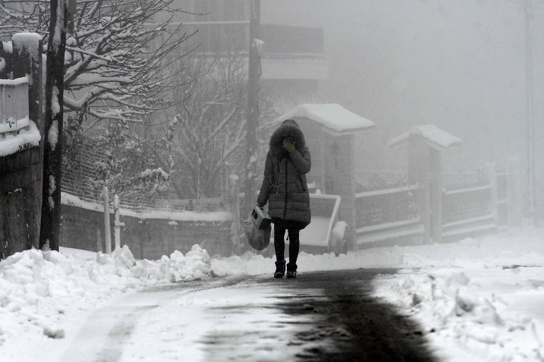 A woman walks outside during a heavy snowfall in Hortiatis, 40km north of Thessaloniki, on January 3, 2019. - Greece is feeling the effects of the extreme weather front "Sophia", as the low barometric started to cover the country from January 2, 2019 night, "Sophia" is expected to bring very low temperatures, strong winds and heavy snowfall across Greece. (Photo by Sakis MITROLIDIS / AFP)