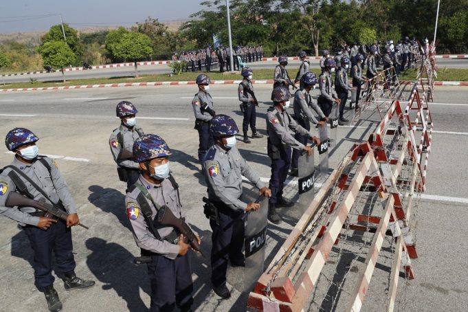 Policemen wearing protective face mask stand guard behind a road barricade, as a part of security preparations ahead of next week's opening of Myanmar's parliament in Naypyitaw, Myanmar, Friday, Jan. 29, 2021. Myanmar's election commission rejected allegations by the military that fraud played a significant role in determining the outcome of November's elections, which delivered a landslide victory to Aung San Suu Kyi's ruling party.(AP Photo/Aung Shine Oo)