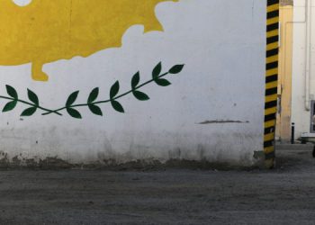 People wearing protective masks walk next to a Cypriot flag painted on a wall in capital Nicosia, Cyprus April 27, 2021. REUTERS/Yiannis Kourtoglou