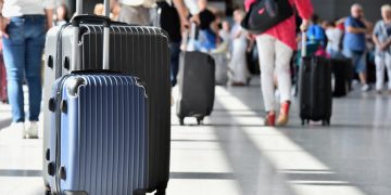 Two plastic travel suitcases in the airport hall.