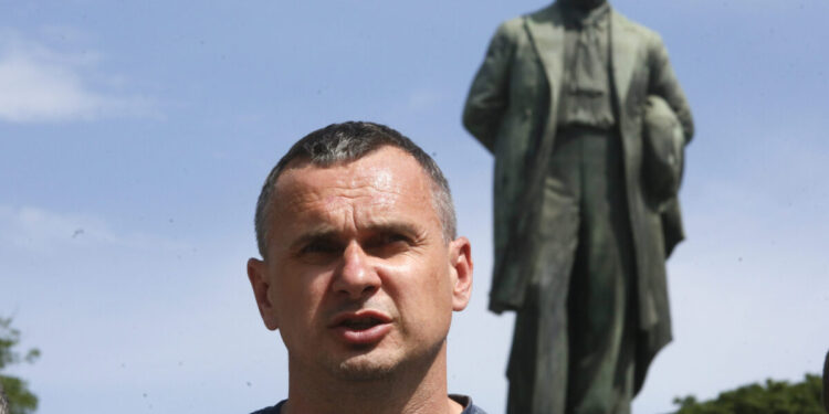 Ukrainian filmmaker and former Russian prisoner Oleg Sentsov, center, talks to reporters during an outdoor press conference in front of a monument to national poet Taras Shevchenko in Kyiv, Ukraine, Friday, June 19, 2020. Sentsov and other former Russian prisoners demanded the Ukrainian authorities to stop political repressions. (AP Photo/Efrem Lukatsky)