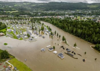 This aerial view taken on August 9, 2023 shows the camping site in Dokka flooded after the Dokka River overflowed its banks. Heavy rains caused flooding and landslides in Sweden and Norway on August 8 while strong winds caused a Danish wildfire to spread out of control, authorities said, with more heavy rain forecast. A storm dubbed "Hans" swept in over the Nordic countries over the weekend, leaving a path of destruction. Norway police reported several landslides in the southeast, with media reporting that over 100 people had been evacuated as a result. (Photo by Stian Lysberg Solum / NTB / AFP) / Norway OUT