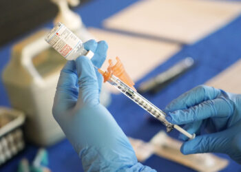 FILE - A nurse prepares a syringe of a COVID-19 vaccine at an inoculation station in Jackson, Miss., Tuesday, July 19, 2022. On Thursday, Oct. 20, 2022, a panel of U.S. vaccine experts said COVID-19 shots should be added to the lists of recommended vaccinations for kids and adults. (AP Photo/Rogelio V. Solis, File)