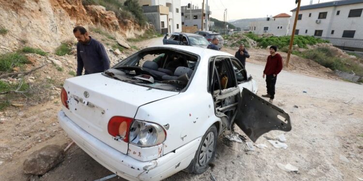 epa11045360 Palestinians inspect a damaged car after an Israeli army raid at Nur Shams refugee camp, near the West Bank town of Tulkarem, 27 December 2023. At least six Palestinians were killed and several others wounded in Israeli military raids and strikes on the refugee camp, the Palestinian Health Ministry said.  EPA/ALAA BADARNEH