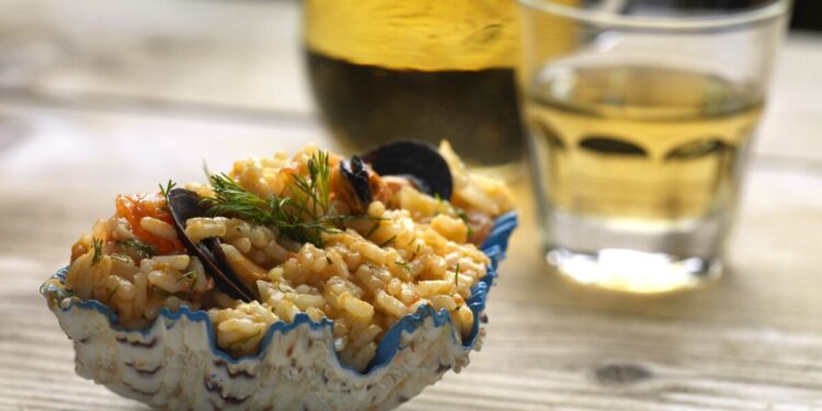 an aromatic risotto with mussels served in a shell with a glass of greek wine(retsina)