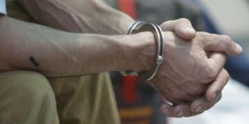 A handcuffed Spanish prisoner waits at a police base near the airport before his repatriation, in Callao, Peru, Thursday, March 16, 2017. A group of 50 Spanish citizens serving out long drug sentences are anxiously awaiting to be repatriated Thursday as part of an airlift brokered by the two governments. Peru is the world's second-largest cocaine producer, and much of the narcotics arriving in Europe passes through Spain, where traffickers prowl for recruits, offering a hefty sum to travel to Lima and bring back cocaine. There are currently more than 200 Spaniards in Peruvian prisons on drug charges, more inmates than from any other foreign country.  (AP Photo/Martin Mejia)