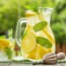 Lemonade pitcher with lemon, mint and ice on garden table