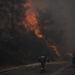 Firefighters inspect flames near a road in Varnava village during a wildfire, north of Athens, Greece, Sunday, Aug. 11, 2024, with many regions of the country on high alert due to high temperatures and wind speeds. (AP Photo/Michael Varaklas)