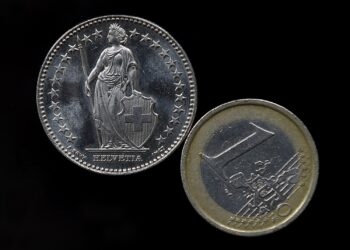 A Euro coin, right, and a Swiss Franc coin  have been placed on a table to be photographed in Gelsenkirchen, Germany, Thursday, Jan. 15, 2015. The European currency has  lost value after Switzerland's central bank said Thursday it has scrapped a policy that limited how much the euro could fall against the Swiss franc, an unexpected decision that caused gyrations in financial markets. (AP Photo/Martin Meissner)