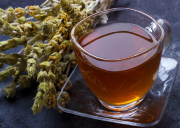 Mountain tea. Sideritis herbal tea and flowers on black slate stone selective focus