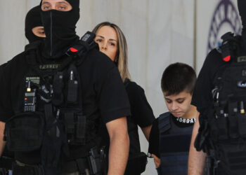 ΣΗΜΕΙΩΣΗ ΓΙΑ ΤΟΥΣ EDITORS. ΠΡΟΣΟΧΗ: Η φωτογραφία έχει ληφθεί χωρίς τη ρητή άδεια των εικονιζόμενων. Η δημοσίευση των χαρακτηριστικών τους γίνεται αποκλειστικά με ευθύνη του συνδρομητή. Η Ειρήνη Μουρτζούκου συνοδευόμενη από άνδρες της ΕΛΑΣ αναχωρεί από την ΓΑΔΑ προκειμένου να πάει στην Πάτρα, στον ανακριτή Αχαΐας μετά την σύλληψη της από το Τμήμα Εγκλημάτων Κατά Ζωής της Διεύθυνσης Οργανωμένου Εγκλήματος κατόπιν σχετικού εντάλματος από τον ανακριτή Αχαΐας για ανθρωποκτονία με δόλο κατά συρροή τετελεσμένη και σε απόπειρα κατ΄εξακολούθηση και μη. Κατηγορείται για τη δολοφονία των δύο παιδιών της και ενός ακόμη βρέφους καθώς και για μια απόπειρα δολοφονίας μιας ενήλικης γυναίκας. Κυριακή 13 Ιουλίου 2025. ΑΠΕ-ΜΠΕ/ΑΠΕ-ΜΠΕ/ΑΛΕΞΑΝΔΡΟΣ ΒΛΑΧΟΣ